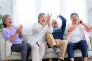 Happiness of the group females and male elderly sitting on the sofa. Senior people are talking and enjoy together at the living room. Joyful carefree retired senior friends enjoying relaxation. photo