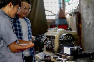 Men are inspecting steel parts for machine installation. team of teacher and student are learning to use heavy machines in steel factory. workers cooperate while doing quality control of manufactured. photo