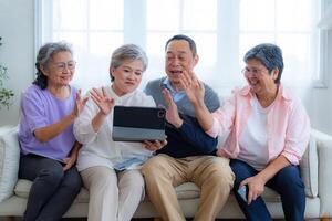 Happiness of the group females and male elderly talking with Call from smart tablet. Senior people are talking and enjoy together at the living room. Joyful retired friends enjoying relaxation. photo