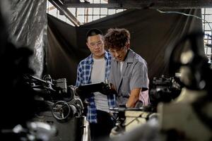Men are inspecting steel parts for machine installation. team of teacher and student are learning to use heavy machines in steel factory. workers cooperate while doing quality control of manufactured. photo