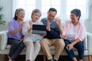 Happiness of the group females and male elderly talking with Call from smart tablet. Senior people are talking and enjoy together at the living room. Joyful retired friends enjoying relaxation. photo