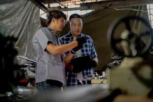 Men are inspecting steel parts for machine installation. team of teacher and student are learning to use heavy machines in steel factory. workers cooperate while doing quality control of manufactured. photo