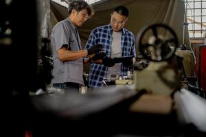 Men are inspecting steel parts for machine installation. team of teacher and student are learning to use heavy machines in steel factory. workers cooperate while doing quality control of manufactured. photo