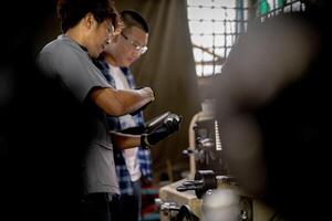 Men are inspecting steel parts for machine installation. team of teacher and student are learning to use heavy machines in steel factory. workers cooperate while doing quality control of manufactured. photo