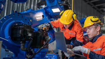 group of male engineer workers maintenance automatic robotic arm machine in a dark room factory. worker checking and repairing automatic robot hand machine. Worker wearing safety glasses and helmet. photo