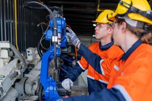 group of male engineer workers maintenance automatic robotic arm machine in a dark room factory. worker checking and repairing automatic robot hand machine. Worker wearing safety glasses and helmet. photo