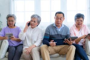Happiness of the group females and male elderly talking with Call from smart tablet. Senior people are talking and enjoy together at the living room. Joyful retired friends enjoying relaxation. photo