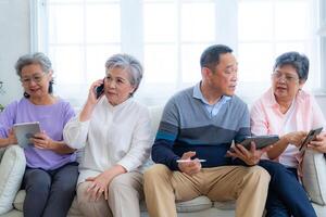Happiness of the group females and male elderly talking with Call from smart tablet. Senior people are talking and enjoy together at the living room. Joyful retired friends enjoying relaxation. photo