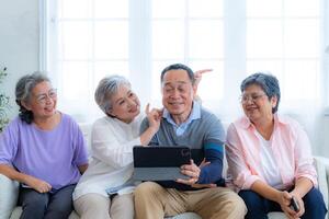 Happiness of the group females and male elderly talking with Call from smart tablet. Senior people are talking and enjoy together at the living room. Joyful retired friends enjoying relaxation. photo