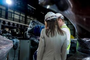 team engineers inspecting on machine with smart tablet. Worker works at heavy machine robot arm. The welding machine with a remote system in an industrial factory. Artificial intelligence concept. photo