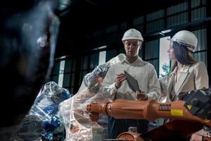 team engineers inspecting on machine with smart tablet. Worker works at heavy machine robot arm. The welding machine with a remote system in an industrial factory. Artificial intelligence concept. photo