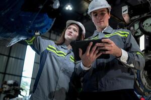 team engineers inspecting on machine with smart tablet. Worker works at heavy machine robot arm. The welding machine with a remote system in an industrial factory. Artificial intelligence concept. photo