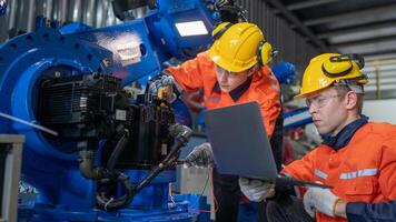 group of male engineer workers maintenance automatic robotic arm machine in a dark room factory. worker checking and repairing automatic robot hand machine. Worker wearing safety glasses and helmet. photo
