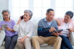 Happiness of the group females and male elderly talking with Call from smart tablet. Senior people are talking and enjoy together at the living room. Joyful retired friends enjoying relaxation. photo