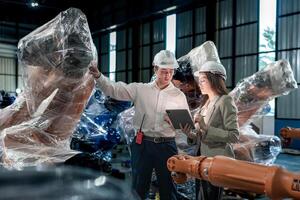 team engineers inspecting on machine with smart tablet. Worker works at heavy machine robot arm. The welding machine with a remote system in an industrial factory. Artificial intelligence concept. photo