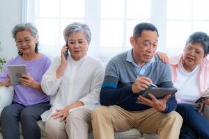 Happiness of the group females and male elderly talking with Call from smart tablet. Senior people are talking and enjoy together at the living room. Joyful retired friends enjoying relaxation. photo