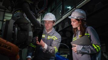 team engineers inspecting on machine with smart tablet. Worker works at heavy machine robot arm. The welding machine with a remote system in an industrial factory. Artificial intelligence concept. photo