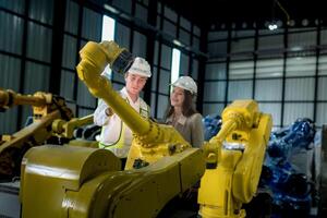 team engineers inspecting on machine with smart tablet. Worker works at heavy machine robot arm. The welding machine with a remote system in an industrial factory. Artificial intelligence concept. photo