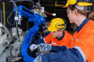 group of male engineer workers maintenance automatic robotic arm machine in a dark room factory. worker checking and repairing automatic robot hand machine. Worker wearing safety glasses and helmet. photo