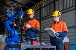 group of male engineer workers maintenance automatic robotic arm machine in a dark room factory. worker checking and repairing automatic robot hand machine. Worker wearing safety glasses and helmet. photo