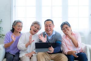 Happiness of the group females and male elderly talking with Call from smart tablet. Senior people are talking and enjoy together at the living room. Joyful retired friends enjoying relaxation. photo