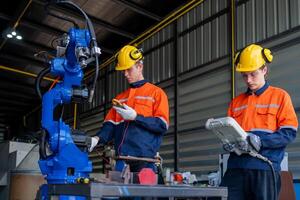 group of male engineer workers maintenance automatic robotic arm machine in a dark room factory. worker checking and repairing automatic robot hand machine. Worker wearing safety glasses and helmet. photo