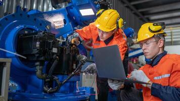 group of male engineer workers maintenance automatic robotic arm machine in a dark room factory. worker checking and repairing automatic robot hand machine. Worker wearing safety glasses and helmet. photo