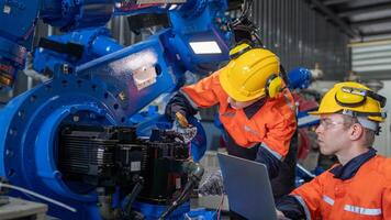 group of male engineer workers maintenance automatic robotic arm machine in a dark room factory. worker checking and repairing automatic robot hand machine. Worker wearing safety glasses and helmet. photo