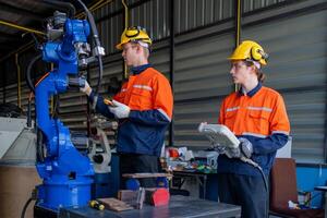 group of male engineer workers maintenance automatic robotic arm machine in a dark room factory. worker checking and repairing automatic robot hand machine. Worker wearing safety glasses and helmet. photo