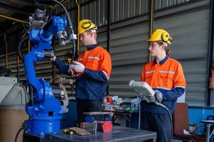 group of male engineer workers maintenance automatic robotic arm machine in a dark room factory. worker checking and repairing automatic robot hand machine. Worker wearing safety glasses and helmet. photo