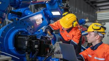 group of male engineer workers maintenance automatic robotic arm machine in a dark room factory. worker checking and repairing automatic robot hand machine. Worker wearing safety glasses and helmet. photo