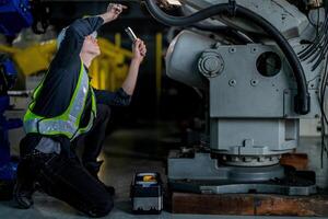 male engineer workers maintenance automatic robotic arm machine in a factory. worker checking and repairing automatic robot hand machine. technician worker check for repair factory machine. photo