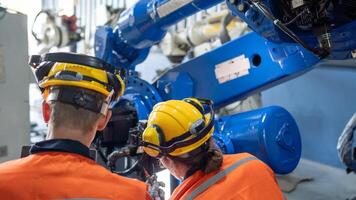 group of male engineer workers maintenance automatic robotic arm machine in a dark room factory. worker checking and repairing automatic robot hand machine. Worker wearing safety glasses and helmet. photo