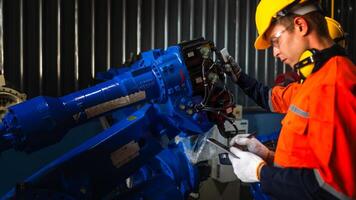 group of male engineer workers maintenance automatic robotic arm machine in a dark room factory. worker checking and repairing automatic robot hand machine. Worker wearing safety glasses and helmet. photo