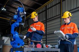 group of male engineer workers maintenance automatic robotic arm machine in a dark room factory. worker checking and repairing automatic robot hand machine. Worker wearing safety glasses and helmet. photo