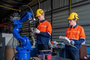 group of male engineer workers maintenance automatic robotic arm machine in a dark room factory. worker checking and repairing automatic robot hand machine. Worker wearing safety glasses and helmet. photo