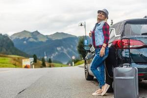 woman in the summer goes on vacation, on vacation with an suitcase on the background of nature and mountains. The concept of travel, weekend in a beautiful place in the mountains photo