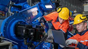 group of male engineer workers maintenance automatic robotic arm machine in a dark room factory. worker checking and repairing automatic robot hand machine. Worker wearing safety glasses and helmet. photo