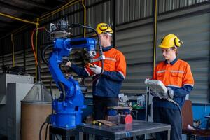 group of male engineer workers maintenance automatic robotic arm machine in a dark room factory. worker checking and repairing automatic robot hand machine. Worker wearing safety glasses and helmet. photo