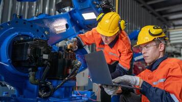 group of male engineer workers maintenance automatic robotic arm machine in a dark room factory. worker checking and repairing automatic robot hand machine. Worker wearing safety glasses and helmet. photo
