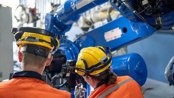 group of male engineer workers maintenance automatic robotic arm machine in a dark room factory. worker checking and repairing automatic robot hand machine. Worker wearing safety glasses and helmet. photo