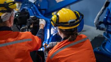 group of male engineer workers maintenance automatic robotic arm machine in a dark room factory. worker checking and repairing automatic robot hand machine. Worker wearing safety glasses and helmet. photo