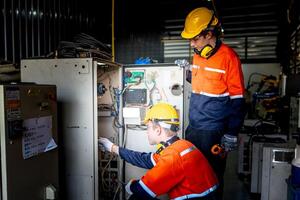 group of male engineer workers maintenance automatic robotic arm machine in a dark room factory. worker checking and repairing automatic robot hand machine. Worker wearing safety glasses and helmet. photo