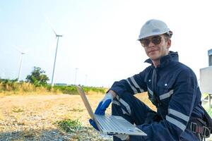 A technician in safety gear meticulously records data with a wind turbine in the backdrop at dusk. photo
