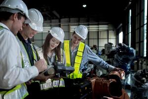 team engineers inspecting on machine with smart tablet. Worker works at heavy machine robot arm. The welding machine with a remote system in an industrial factory. Artificial intelligence concept. photo