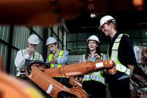 team engineers inspecting on machine with smart tablet. Worker works at heavy machine robot arm. The welding machine with a remote system in an industrial factory. Artificial intelligence concept. photo
