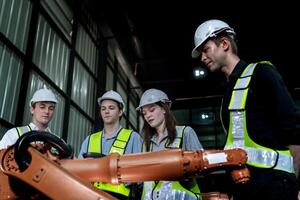 team engineers inspecting on machine with smart tablet. Worker works at heavy machine robot arm. The welding machine with a remote system in an industrial factory. Artificial intelligence concept. photo