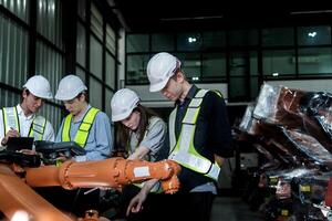 team engineers inspecting on machine with smart tablet. Worker works at heavy machine robot arm. The welding machine with a remote system in an industrial factory. Artificial intelligence concept. photo