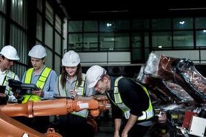 team engineers inspecting on machine with smart tablet. Worker works at heavy machine robot arm. The welding machine with a remote system in an industrial factory. Artificial intelligence concept. photo