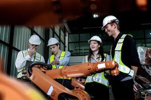 team engineers inspecting on machine with smart tablet. Worker works at heavy machine robot arm. The welding machine with a remote system in an industrial factory. Artificial intelligence concept. photo